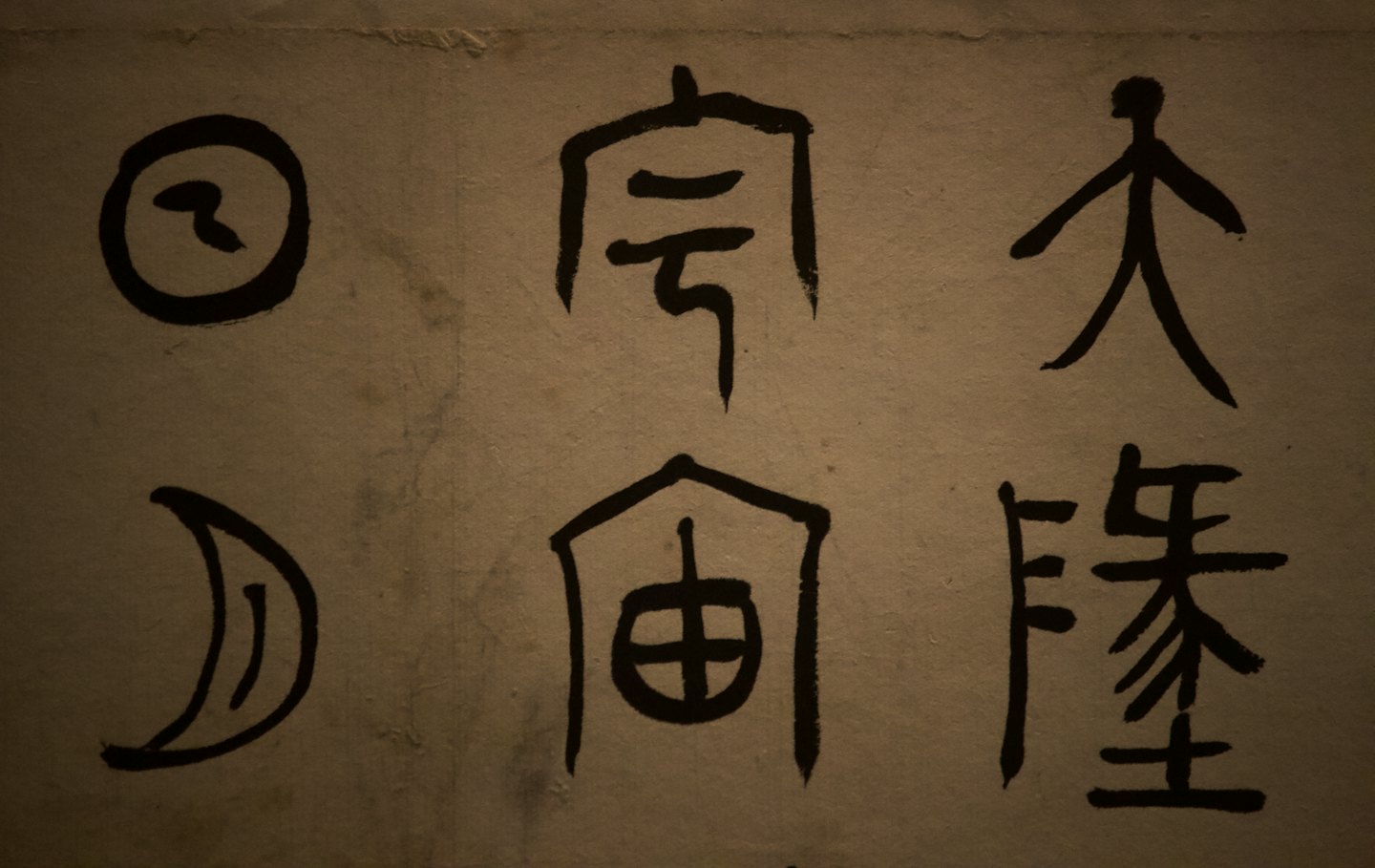 Six ancient Chinese characters drawn in black ink on beige parchment.